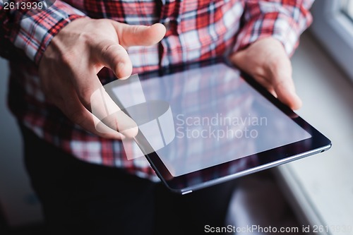 Image of The man uses a tablet PC. Modern gadget in hand.