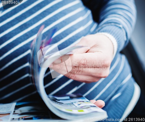 Image of A man looks at a magazine. Press hands.