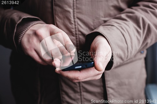 Image of The man is using a smartphone. Modern mobile phone in hand.