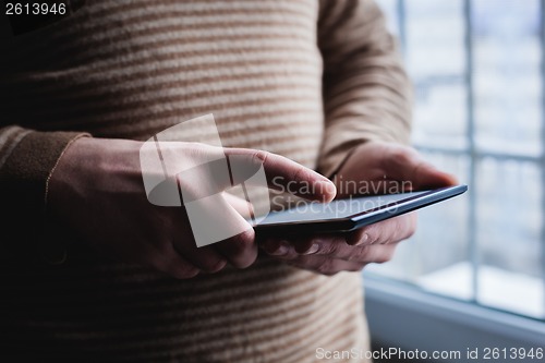 Image of The man uses a tablet PC. Modern gadget in hand.