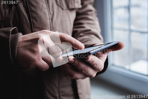 Image of The man uses a tablet PC. Modern gadget in hand.