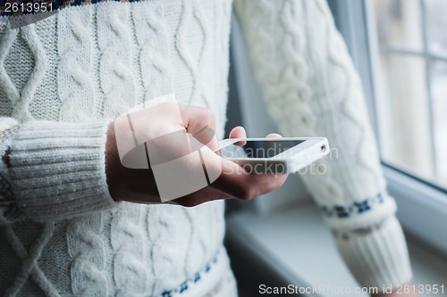 Image of The man is using a smartphone. Modern mobile phone in hand.