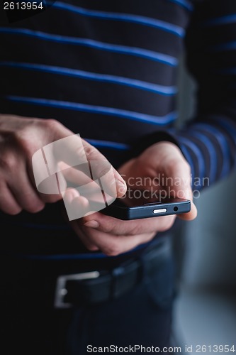 Image of The man is using a smartphone. Modern mobile phone in hand.