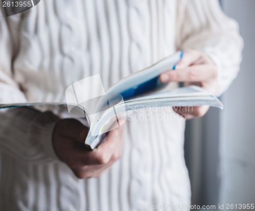 Image of A man looks at a magazine. Press hands.