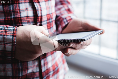 Image of The man uses a tablet PC. Modern gadget in hand.