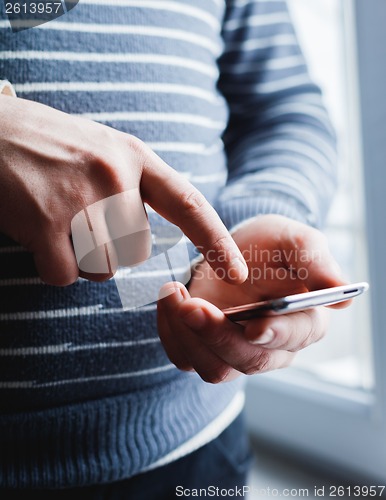 Image of The man is using a smartphone. Modern mobile phone in hand.