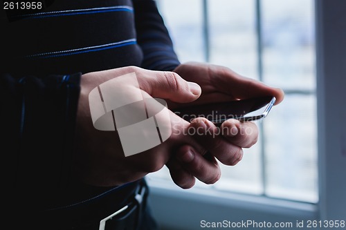 Image of The man is using a smartphone. Modern mobile phone in hand.