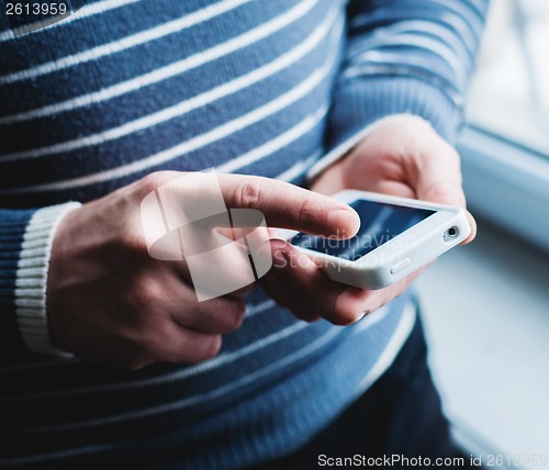 Image of The man is using a smartphone. Modern mobile phone in hand.
