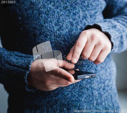 Image of The man is using a smartphone. Modern mobile phone in hand.