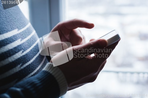 Image of The man is using a smartphone. Modern mobile phone in hand.