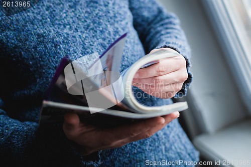 Image of A man looks at a magazine. Press hands.