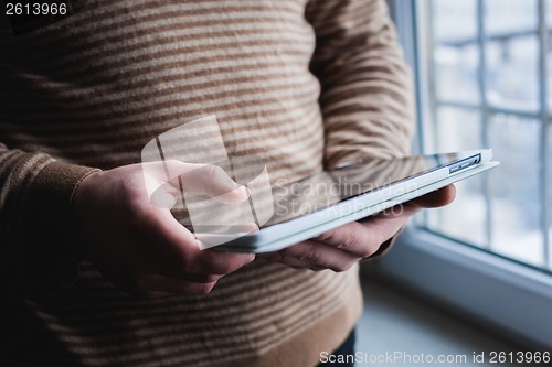 Image of The man uses a tablet PC. Modern gadget in hand.