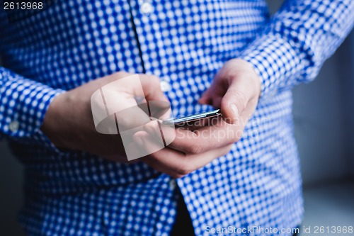 Image of The man is using a smartphone. Modern mobile phone in hand.