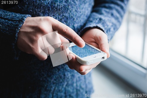 Image of The man is using a smartphone. Modern mobile phone in hand.