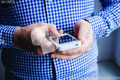 Image of The man is using a smartphone. Modern mobile phone in hand.