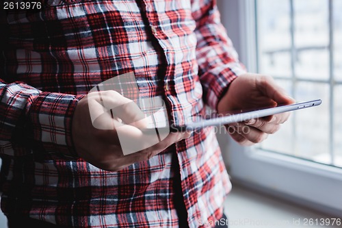 Image of The man uses a tablet PC. Modern gadget in hand.
