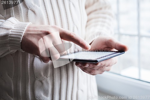 Image of The man uses a tablet PC. Modern gadget in hand.