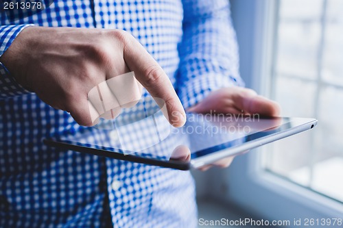 Image of The man uses a tablet PC. Modern gadget in hand.