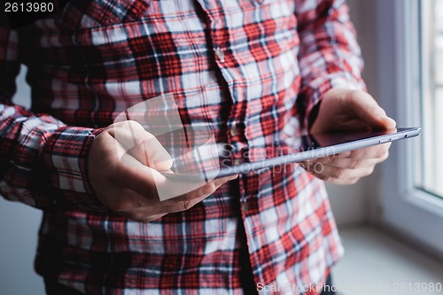 Image of The man uses a tablet PC. Modern gadget in hand.