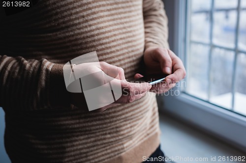 Image of The man is using a smartphone. Modern mobile phone in hand.