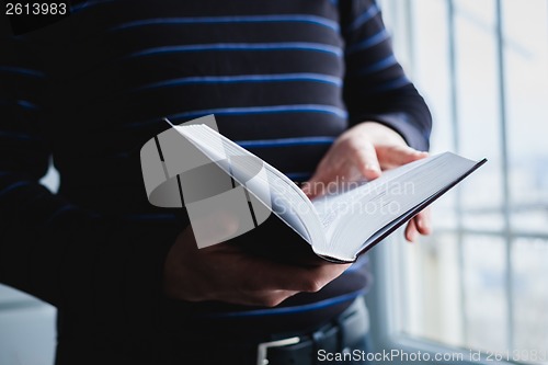 Image of Man reading. Book in his hands.