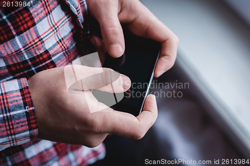 Image of The man is using a smartphone. Modern mobile phone in hand.