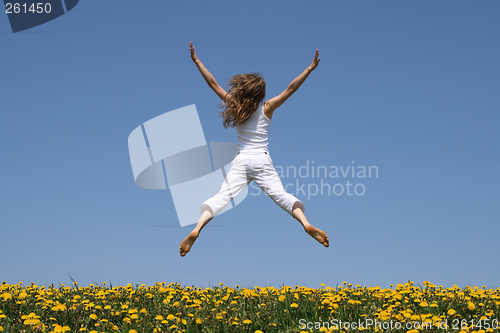 Image of Girl flying in a funny jump over dandelion field