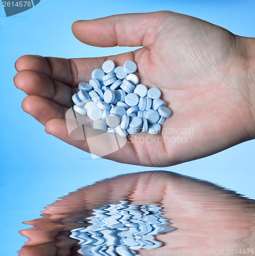 Image of hand holding blue pills