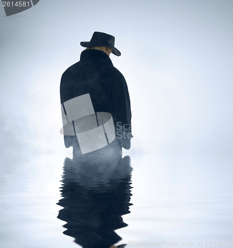 Image of person wearing trench coat and standing in water