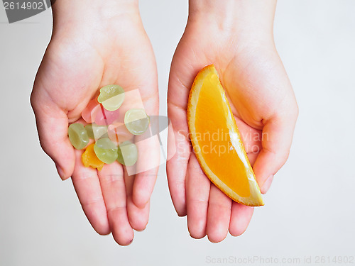 Image of Candies and orange slice in the hands of a child