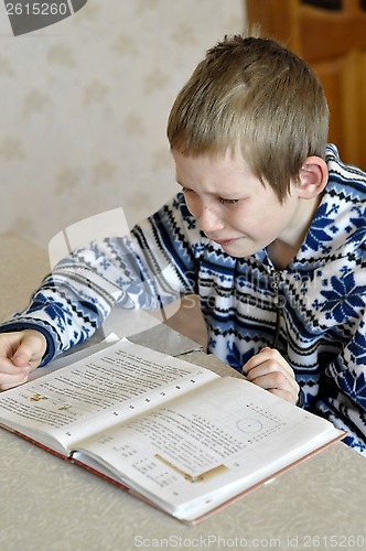 Image of The 10-year-old boy with tears in the eyes sits before the textb