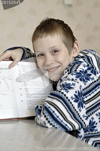 Image of The 10-year-old boy sits with the textbook, doing homework.