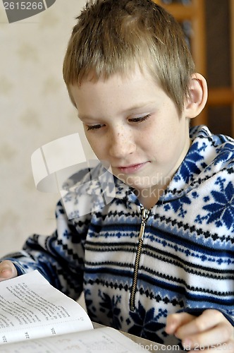 Image of The 10-year-old boy sits with the textbook, doing homework.