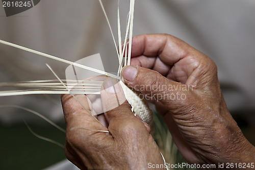 Image of Old woman's hands and wicker straw hat