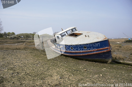 Image of A small boat in the mud of a river estuary