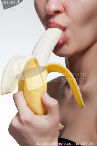 Image of Young woman biting banana isolated on white