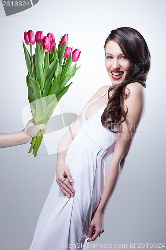 Image of Smiling woman and hand with bouquet of pink tulips on white