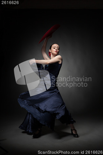 Image of young woman dancing flamenco on black