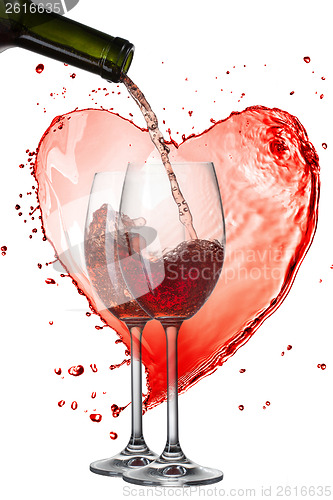 Image of Red wine pouring into glasses with splash against heart isolated