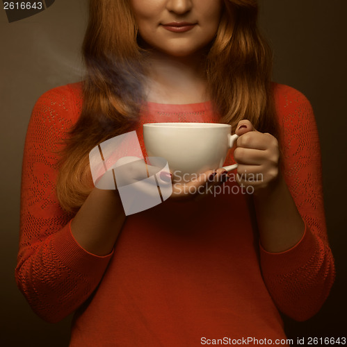 Image of woman holding hot cup and smiles