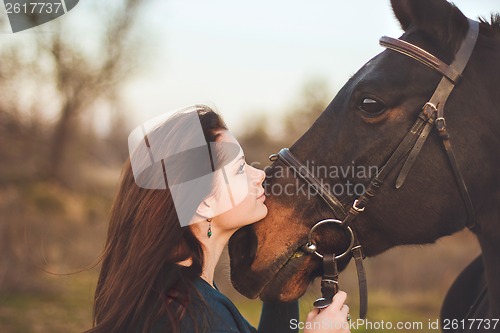 Image of Young woman with a horse on nature