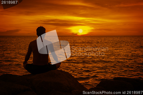 Image of Man meditating at sunset. Tropical beach of Thailand