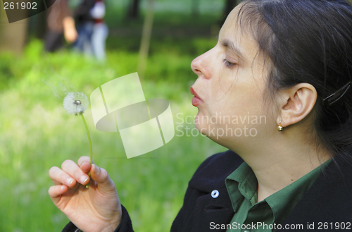 Image of Woman blowing a dandelion