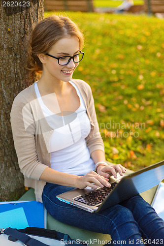 Image of smiling teenager in eyeglasses with laptop