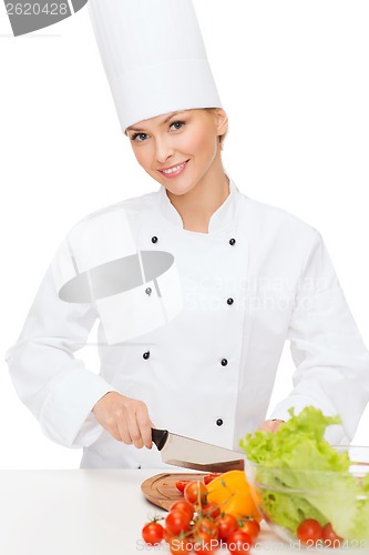 Image of smiling female chef chopping vagetables