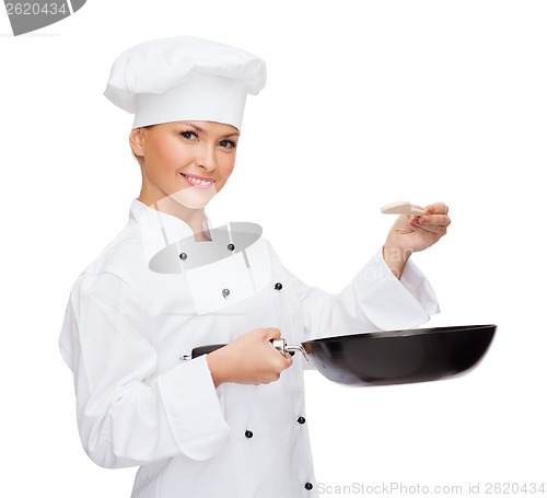 Image of smiling female chef with pan and spoon