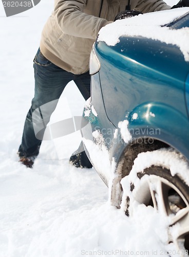 Image of closeup of man pushing car stuck in snow