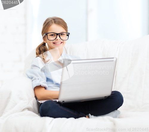 Image of smiling girl in specs with laptop computer at home