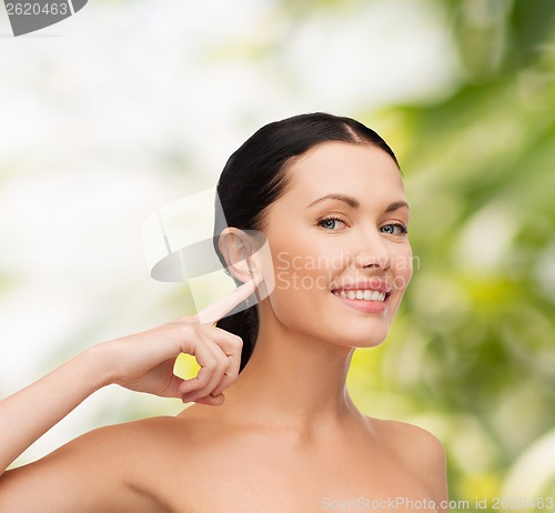 Image of young calm woman pointing to her ear