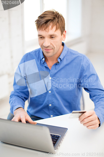 Image of man with laptop and credit card at home